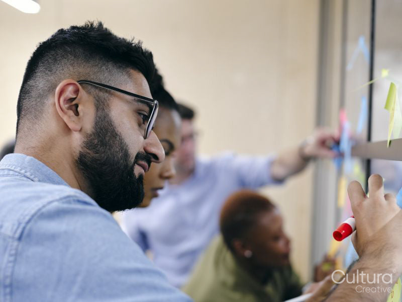 Business people sticking notes to glass wall in office