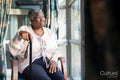 Senior woman with walking cane looking through window