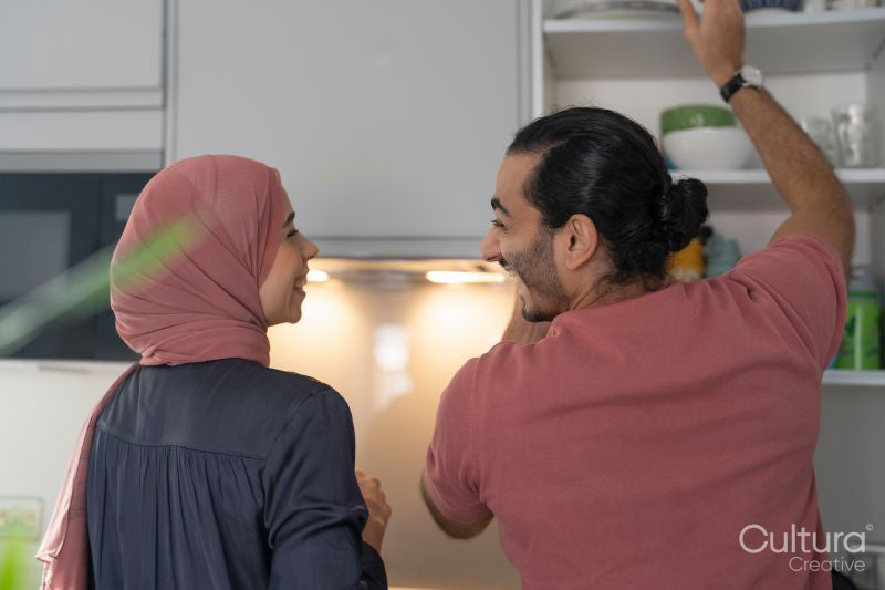 Smiling mid adult couple doing chores together in kitchen