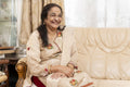 Portrait of cheerful senior woman sitting on sofa in living room