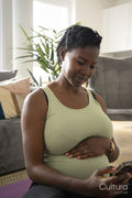 Smiling pregnant woman sitting on yoga mat with smart phone