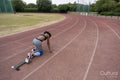 Rear view of female runner on starting blocks at running track