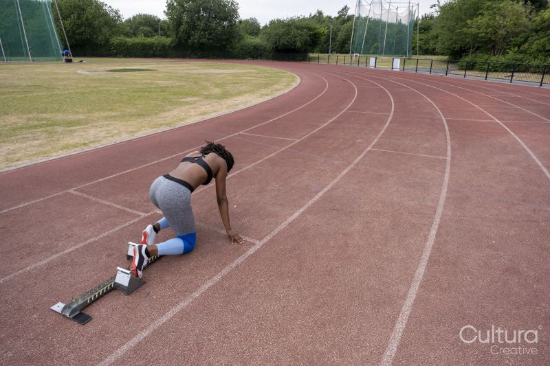 Rear view of female runner on starting blocks at running track