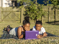Siblings using tablet in back yard