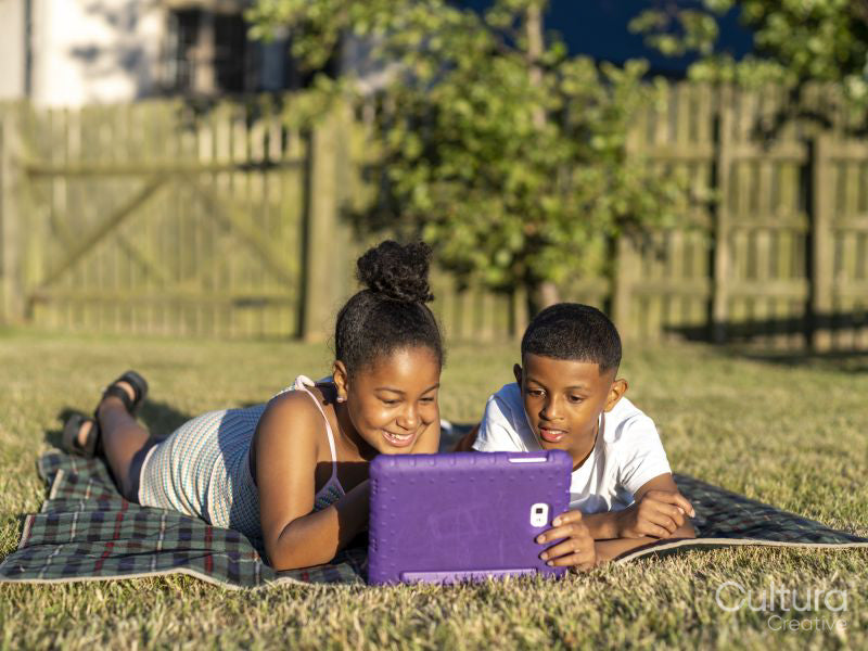 Siblings using tablet in back yard