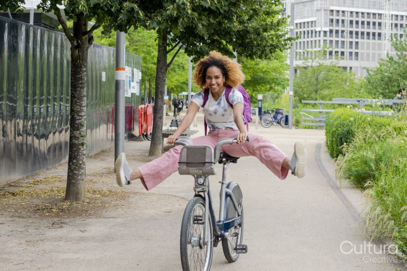 Playful woman cycling with legs outstretched