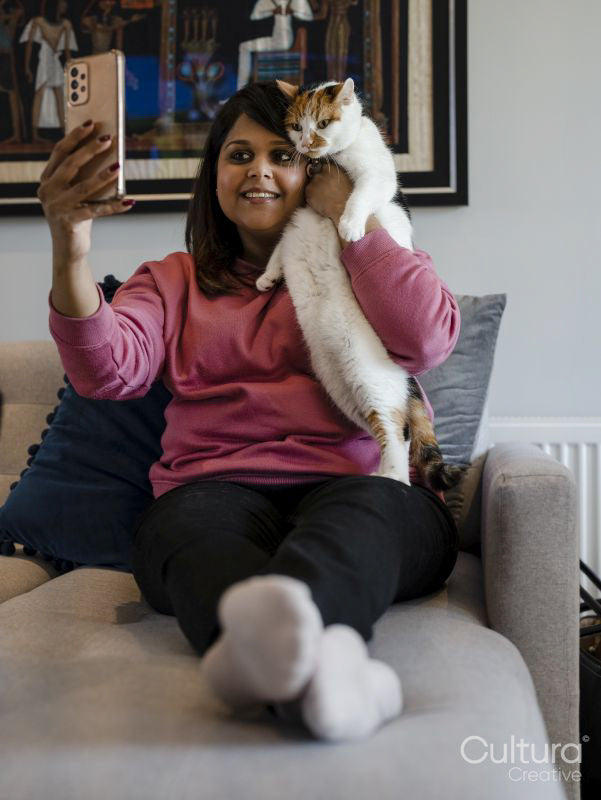Woman taking selfie with cat on sofa