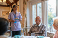 Dietitian serving pancakes to group of seniors at cafeteria in nursing home