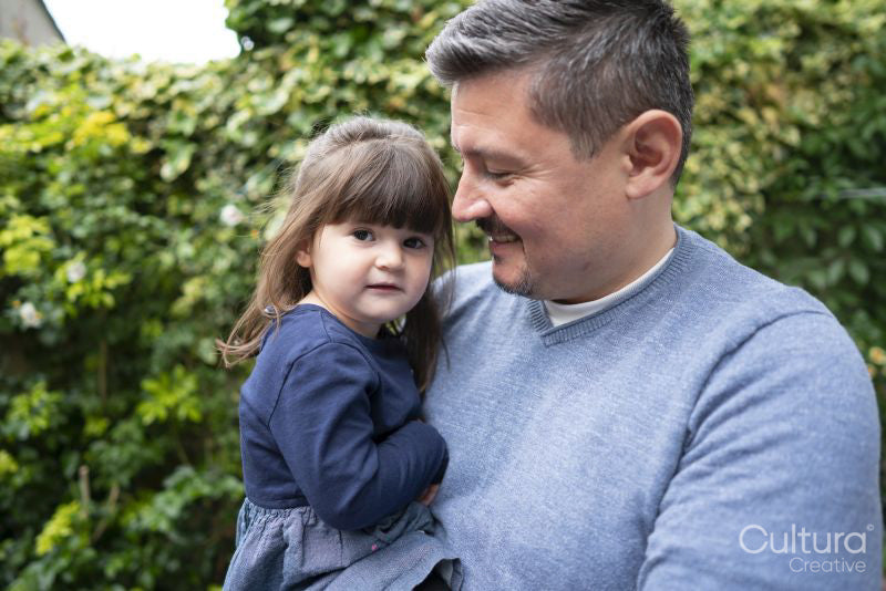Smiling man holding daughter outdoors