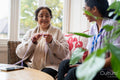 Senior woman knitting and talking to care giver in nursing home