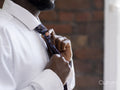 Close-up of person in white shirt tying necktie