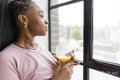 Portrait of serious woman looking through window at home