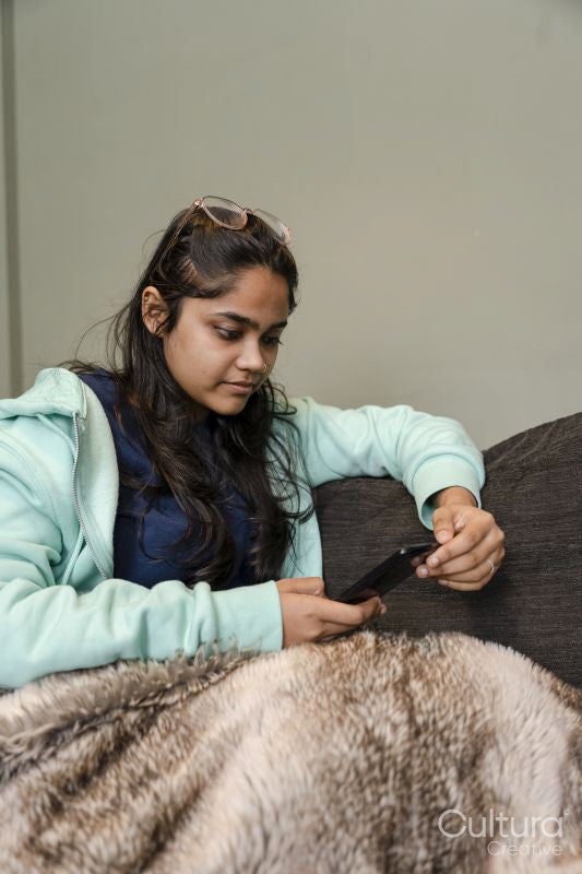 Young woman sitting on sofa and using phone