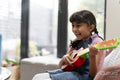 Little girl playing on ukulele in living room