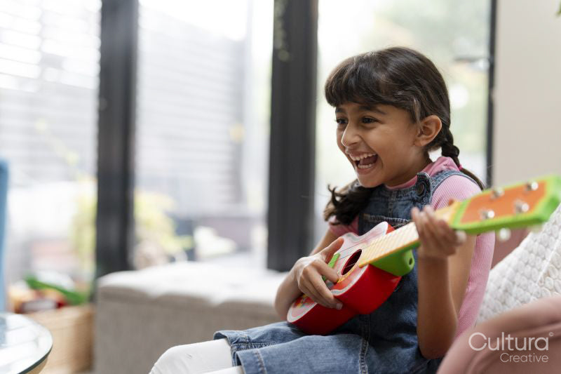 Little girl playing on ukulele in living room