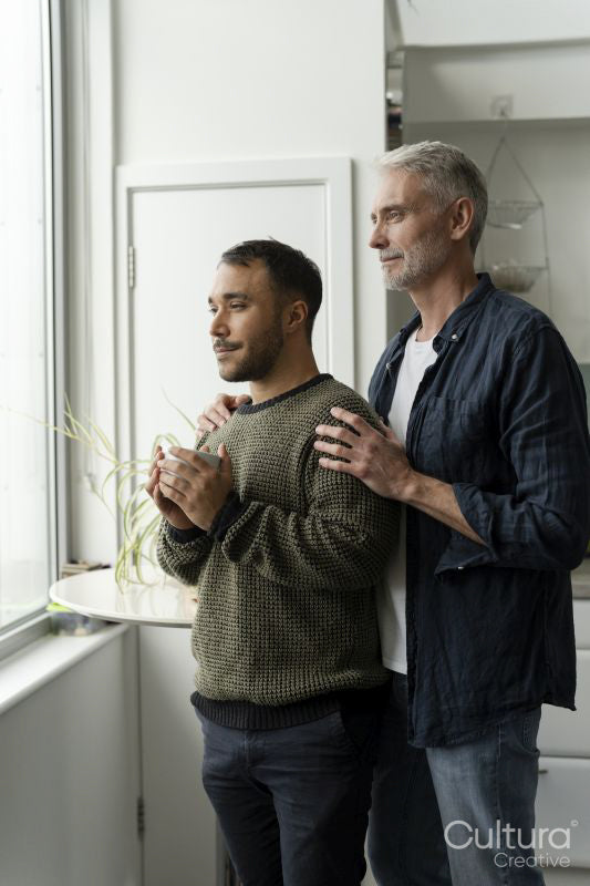 Mature male couple looking through window at home
