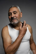 Portrait of man putting on perfume against gray background