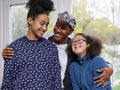 Smiling mother embracing two daughters at home