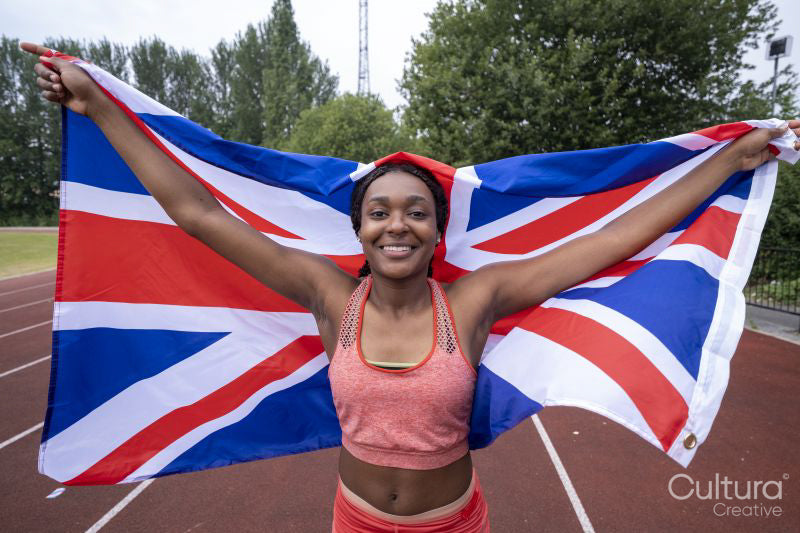 Portrait of smiling athletic woman with British flag on running track