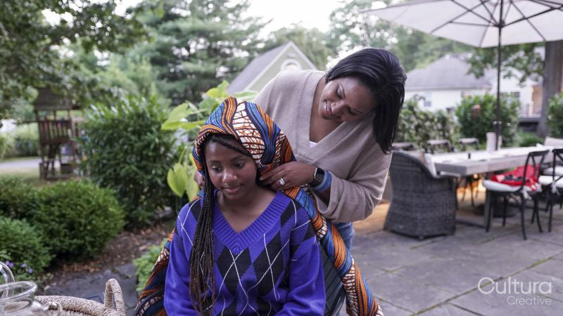 Mother putting traditional headdress on daughter