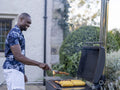 Man grilling corn and meat on barbecue grill