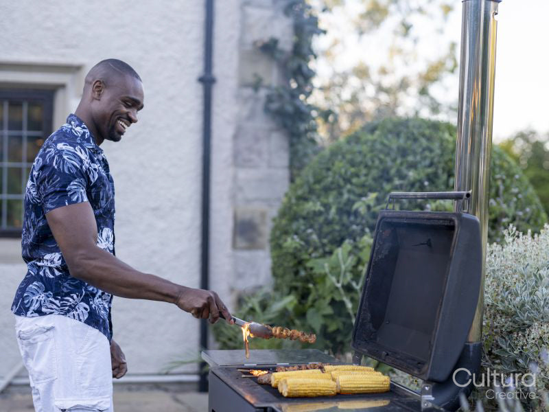 Man grilling corn and meat on barbecue grill