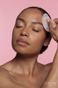 Young woman using face massager