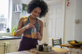 Smiling young woman preparing shake at home