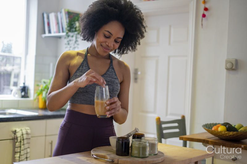 Smiling young woman preparing shake at home