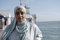 Portrait of Muslim woman looking at camera by sea on sunny day