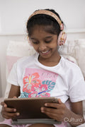 Girl with headphones and tablet sitting on bed