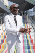 Confident happy man wearing white suit standing on colorful steps