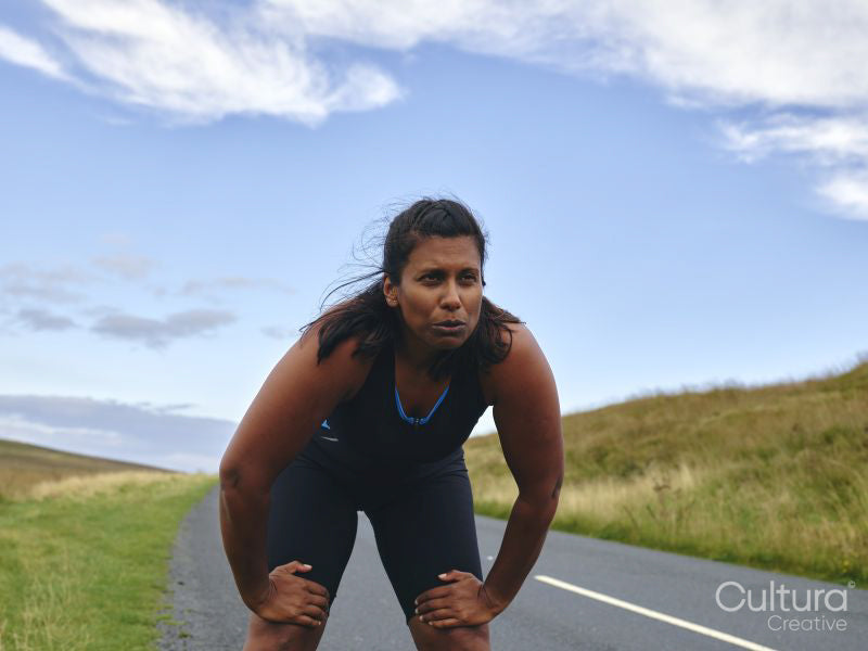 Tired female runner resting on roadside