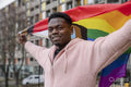 Smiling young man holding progress pride flag