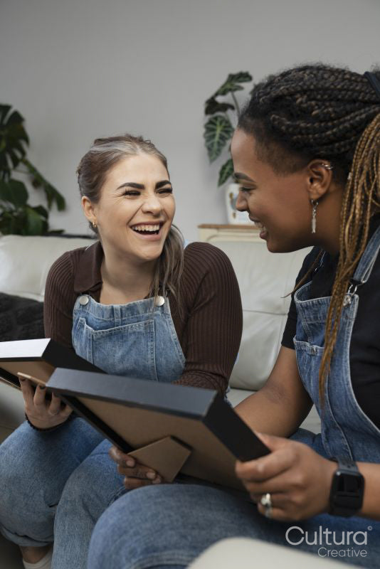 Two young women sitting on sofa looking at photos