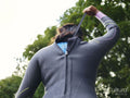Rear view of woman putting on wetsuit