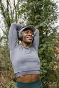 Smiling athletic woman stretching arm in park