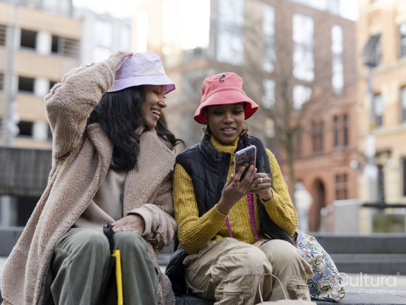 Two young women in urban setting, looking at phone