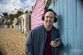 Portrait of man wearing headphones, holding smartphone