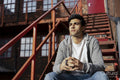 Young man sitting on rusty staircase