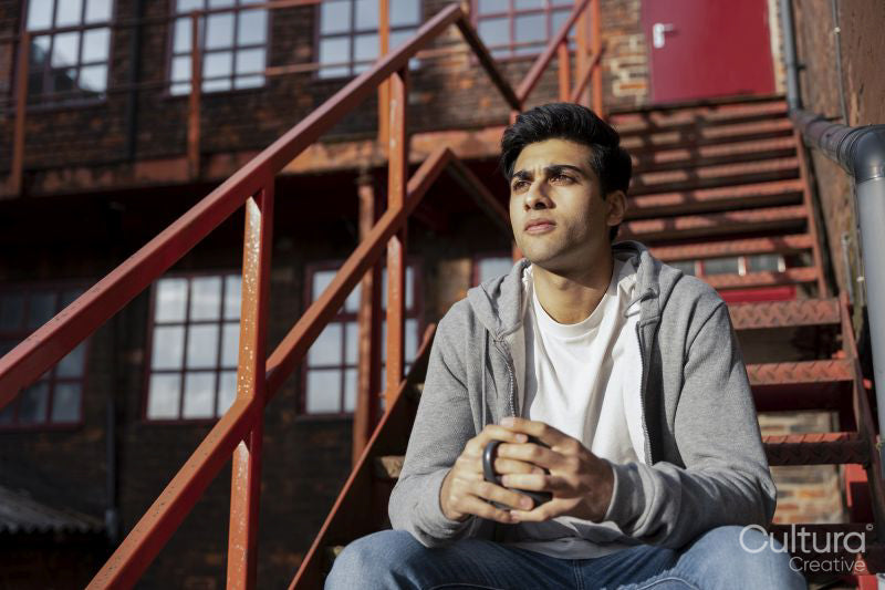 Young man sitting on rusty staircase