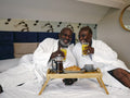 Mature couple enjoying breakfast on bed in hotel room