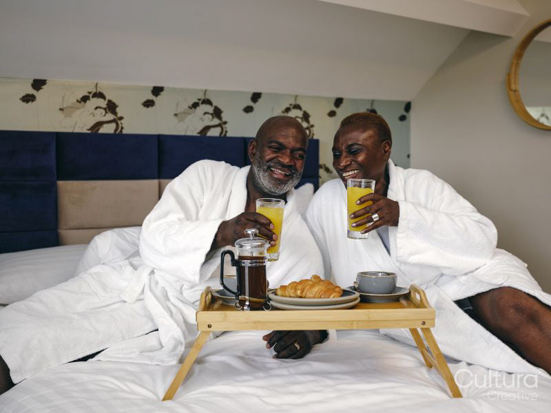 Mature couple enjoying breakfast on bed in hotel room
