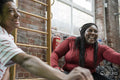 Mother and daughter laughing while doing stretching exercises in gym