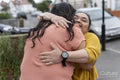 Down syndrome daughter embracing mother on sidewalk