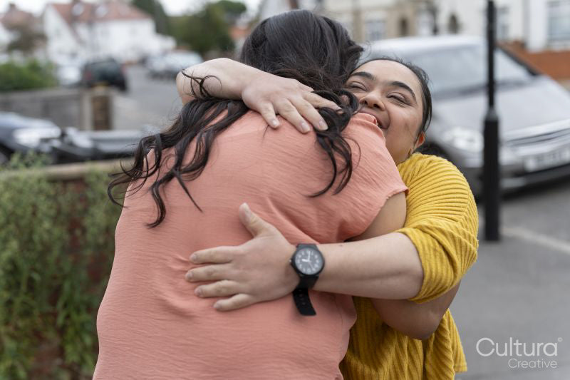 Down syndrome daughter embracing mother on sidewalk