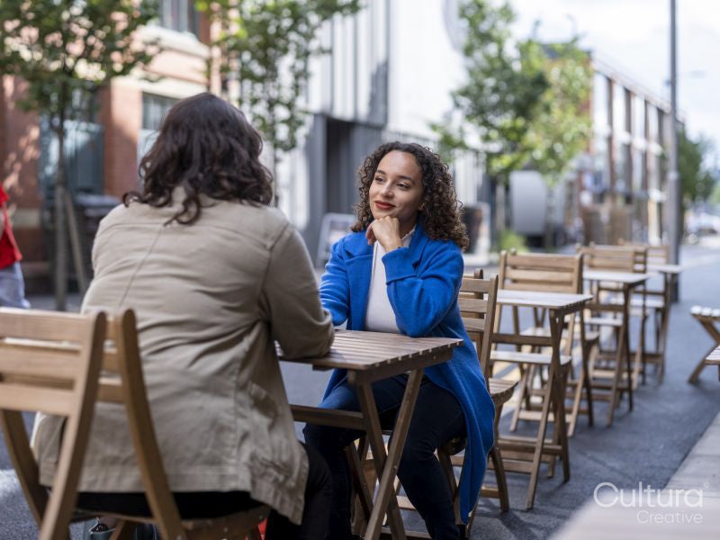 Smiling couple sitting at sidewalk cafe table