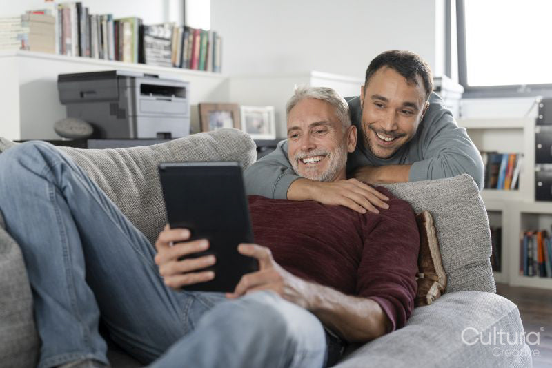 Smiling male couple using digital tablet on sofa