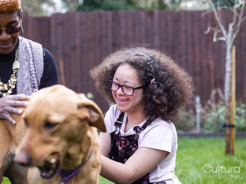 Mother and daughter with dog in backyard