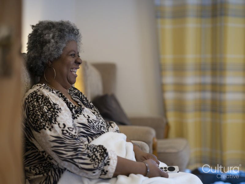 Woman sitting under blanket and watching TV